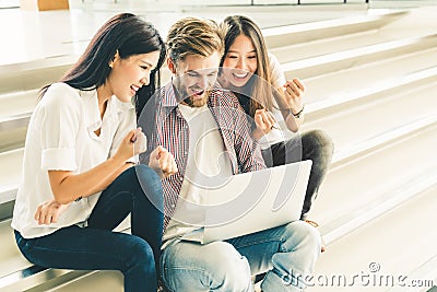 Multiethnic group of college students or young casual freelance team celebrate together using laptop notebook computer Stock Photo