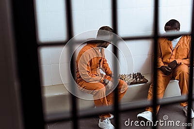 multiethnic prisoners playing chess behind Stock Photo