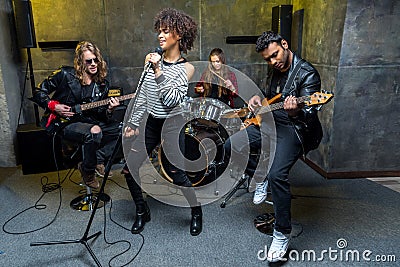 Multiethnic rock and roll band rehearsing in musical studio Stock Photo