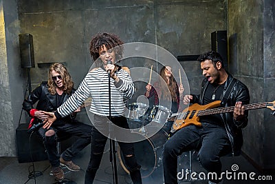 Multiethnic rock and roll band rehearsing in musical studio Stock Photo