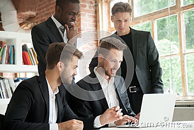 Multiethnic team of corporate employees looking at laptop screen Stock Photo