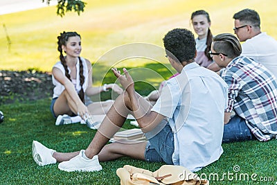 multiethnic teenage students sitting on grass and studying together Stock Photo