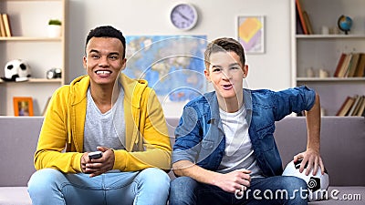 Multiethnic teenager friends emotionally watching football match at home, hobby Stock Photo