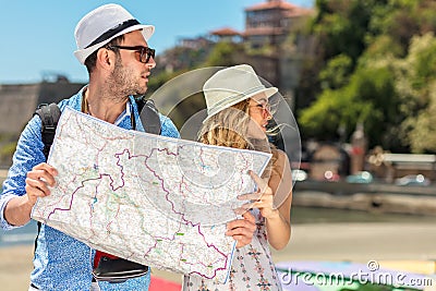 Multiethnic traveler couple using generic local map together on sunny day. Stock Photo