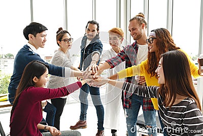 Multiethnic young team stack hands together as trusted unity and teamwork in modern office. Stock Photo