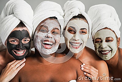 Multigenerational women having fun wearing face beauty mask for skin care therapy - Main focus on african girl face Stock Photo