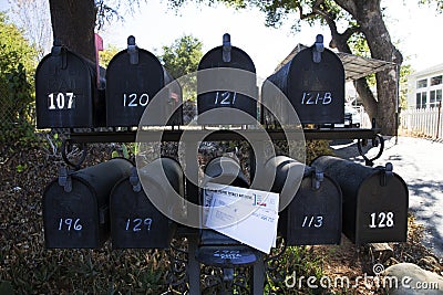 Multiple black mailboxes with one holding mail, Oak View, California, USA Editorial Stock Photo