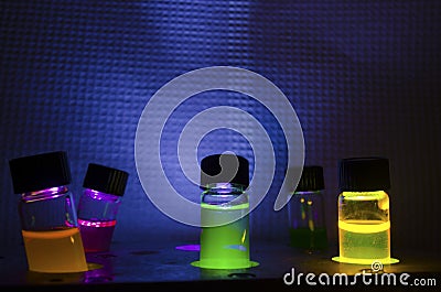Multiple colourful close up photochemical reaction in glass vial under UV light in a dark chemistry laboratory Stock Photo