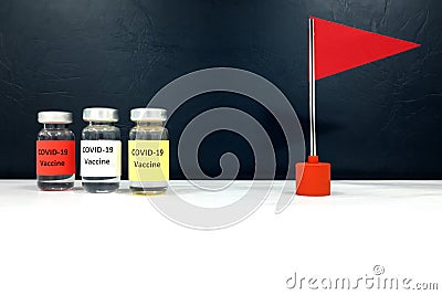 Multiple covid-19 vaccine vials and a red flag. Coronavirus vaccine candidate development race and competition winner concept. Stock Photo