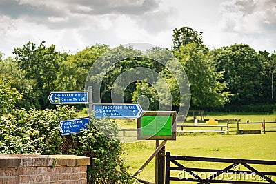 Multiple cycle path and footpath walks seen on blue direction signs near a large horse paddock. Editorial Stock Photo