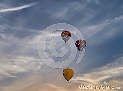 Multiple multi-colored hot air balloons floating in a blue sky with thin clouds. Editorial Stock Photo