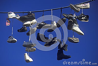 Multiple pairs of shoes flung over electric wire by shoelaces Editorial Stock Photo