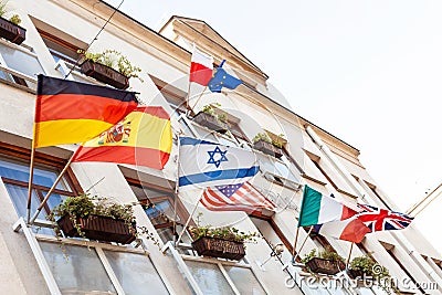 Multiple waving flags on a building facade in the wind, Israel, Germany, Spain, USA, Poland, European Union, Italy, France, UK Stock Photo