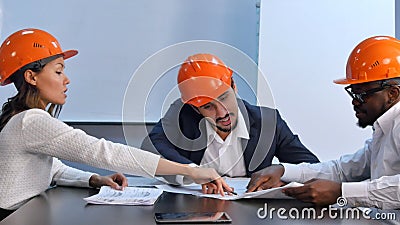 Multiracial colleagues reading construction documents, discussing it Stock Photo