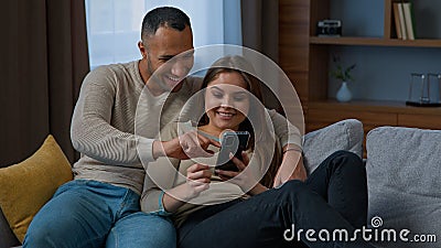 Multiracial couple African American man husband Caucasian woman wife rest on couch together multiethnic happy homeowners Stock Photo