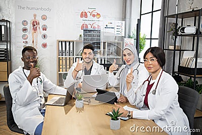 Multiracial doctors showing thumbs up at office meeting Stock Photo