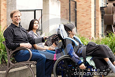 Family with special needs child sitting outdoors together in sum Stock Photo