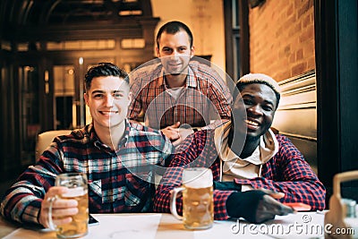 Multiracial friends group drinking and toasting beer at pub. Friendship concept with young people enjoying time together and havin Stock Photo