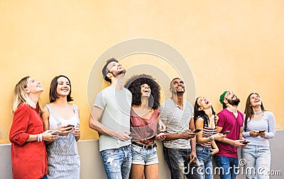 Multiracial friends having fun using smartphone at wall on university college break - Young people addicted by mobile smart phones Stock Photo