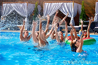 Multiracial group of friends having party in private villa swimming pool. Happy young people in swimwear dancing and Stock Photo