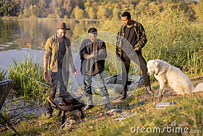 Multiracial group of male friends talking and cooking Ukha on fire Stock Photo