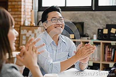 Multiracial group of young creative people in smart casual wear discussing business gesture hand high five, laughing and smiling Stock Photo