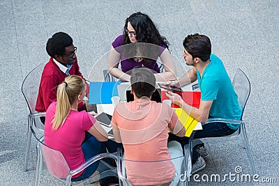 Multiracial group of young students studying together. High angle shot of young people sitting at the table. Stock Photo