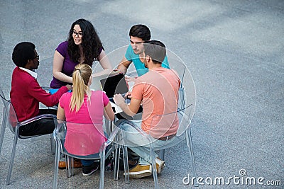 Multiracial group of young students studying together. High angle shot of young people sitting at the table. Stock Photo