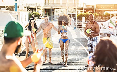 Multiracial happy friends having crazy fun with waterfight battle at summer location - Carefree vacation concept Stock Photo