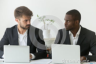 Multiracial office rivals looking at each other, rivalry at work Stock Photo