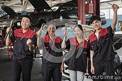 Mechanic workers team celebrating after-work success at a service car garage. Stock Photo