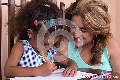 Multiracial small girl and her mother drawing with color pencils Stock Photo