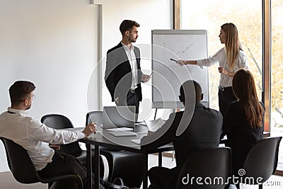 Multiracial team of employees listening to male and female presenters. Stock Photo
