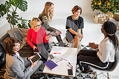 Multiracial women colleagues sitting around the table and drawing graphic Stock Photo