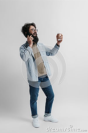 Multitasking Man Laughing on Phone with Coffee in Hand Stock Photo
