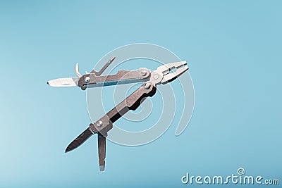 The multitool multi-function tool hovers on a blue background. The concept of an expanded multi-tool with free space Stock Photo