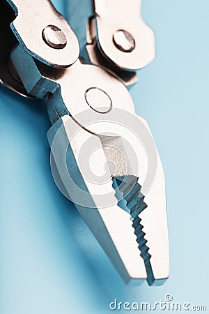 The multitool multi-function tool hovers on a blue background. The concept of an expanded multi-tool with free space Stock Photo