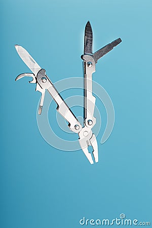The multitool multi-function tool hovers on a blue background. The concept of an expanded multi-tool with free space Stock Photo
