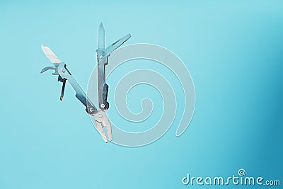 The multitool multi-function tool hovers on a blue background. The concept of an expanded multi-tool with free space Stock Photo