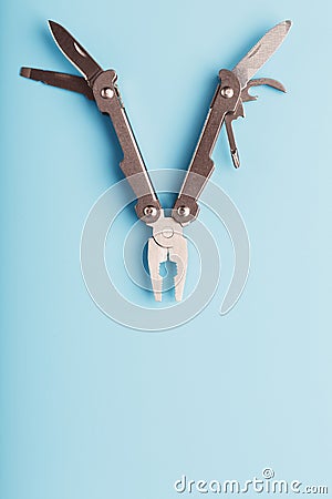 The multitool multi-function tool hovers on a blue background. The concept of an expanded multi-tool with free space Stock Photo