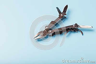 The multitool multi-function tool hovers on a blue background. The concept of an expanded multi-tool with free space Stock Photo