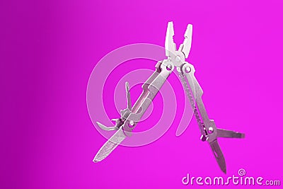 Multitool is a multi-functional tool on a pink background. The concept of an open, flying multi-tool with free space Stock Photo