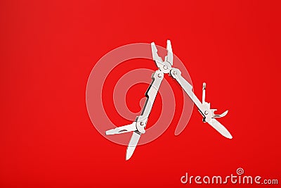 Multitool is a multi-functional tool on a red background. The concept of an open, flying multi-tool with free space Stock Photo