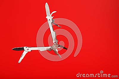 Multitool is a multi-functional tool on a red background. The concept of an open, flying multi-tool with free space Stock Photo