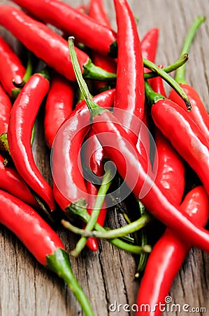 Multitude of red chili peppers on wooden table Stock Photo