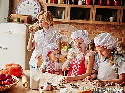 Mum with children in kitchen drinking milk. Cooking girls Stock Photo