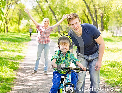 Mum and dad taught his son to ride a bicycle in the park Stock Photo