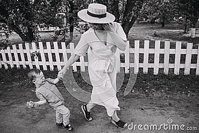 Mum goes with the child in the park. Baby cries and breaks out with a from mom`s hand Stock Photo