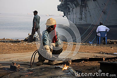 Mumbai/India - 23/11/14 - Ship Breaker Gas Cutter demolishing part of INS Vikrant in Darukhana Ship Breaking Yard Editorial Stock Photo
