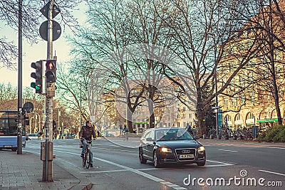 Munich, Germany, December 29, 2016: A car and a bicyclist stand at a traffic light in Munich. City life. Everyday life Editorial Stock Photo